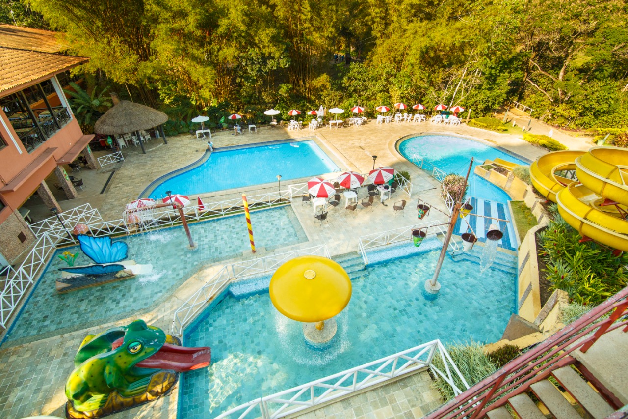 Imagem mostrando as piscinas e brinquedos aquáticos do hotel, tendo toboagua, escorregador em forma de animais (Sapo e borboleta), piscinas rasas e piscinas fundas, ideal para as férias em familia.